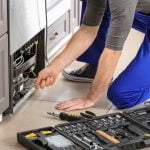 Male technician repairing refrigerator indoors